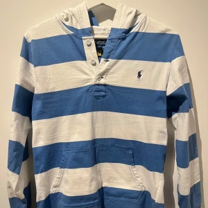 Polo Ralph Lauren Hoodie  - Polo Ralph Lauren Hoodie L14-16, som XS.                                                                              Perfekt till lite varmare tider!                                                                         Skick 10/10 knappt använd.                                            Priset går såklart att diskutera!                                       Vid fler funderingar tveka inte på att slå en signal!                     /VS