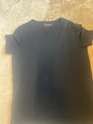 Svart t-shirt från Morris  - Klassisk svart t-shirt från morris använt fåtal par gånger så tröjan är tekniskt sett ny. Varan är äkta köpt på NK för några år sedan. Den har legat i garderoben ett tag nu så jag behöver få den såld och färgen är svart/mörkblå.