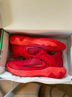 Nike röda sneakers med svart swoosh - Snygga röda Nike sneakers med vågig sula och svart swoosh på sidan. Ovandelen är i mesh och syntetmaterial för bra andningsförmåga och komfort. Skorna har röda skosnören och en chunky, sportig look som sticker ut.