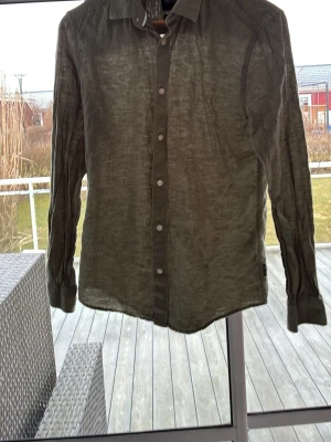 Olivgrön linneskjorta Only & Sons - Snygg olivgrön skjorta från Only & Sons i linne med klassisk krage och vita knappar. Skjortan har lång ärm och en slim passform som ger en modern look. Perfekt för dig som gillar stilrena och luftiga plagg.