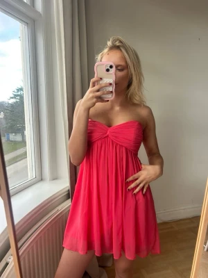 Axelbandslös rosa kortklänning💖💖✨ - Säljer en söt axelbandslös rosa kortklänning med twistad detalj vid bysten och ett luftigt, flowy tyg. Perfekt för sommarens alla tillfällen och ger en riktigt fräsch vibe. OBS ! Den är ish sönder vid dragkedjan dvs går inte att dra upp hela vägen som jag visar , går förmodligen att laga enkelt med olja eller så har inte försökt så💖