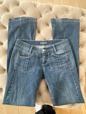 Low waist jeans bootcut  - Säljer ett par klassiska blå jeans från Miss Sixty med raka ben och snygga kontrastsömmar. Jeansen har fem fickor och broderad logga på myntfickan. 