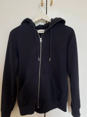 Mörkblå zip hoodie - Mörkblå zip hoodie från H&M med dragkedja framtill och två stora fickor. Zip hoodien har huva med snören och ribbade muddar vid ärmar och nederkant. Storlek S 