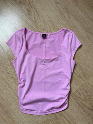 Rosa croppad topp - Söt rosa croppad topp med korta ärmar. Toppen har en tight passform och är gjord i mjuk material, perfekt för en trendig och avslappnad look 