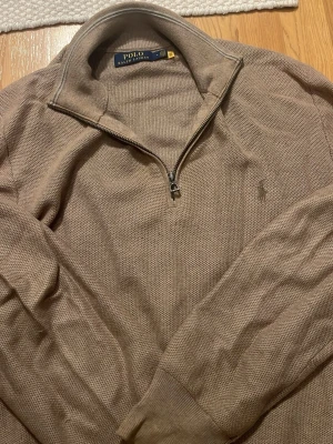 Polo Ralph Lauren, Beige/Brun halvzip  - Snygg beige tröja från Polo Ralph Lauren med halvzip och broderad logga på bröstet. Stickad ull men sticks inte alls. Super skön och snygg nu på våren. Har små defekter men inget som syns. Inga missfärgningar. 
