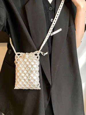 Vit pärlhandväska med axelrem - Superfin handväska i vit pärldesign med rektangulär form och lång axelrem. Väskan är helt täckt av pärlor och har ett unikt, handgjort utseende som verkligen sticker ut. Perfekt accessoar för att lyfta vilken outfit som helst.