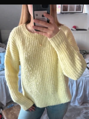 Gul stickad tröja från Zara - Mysig ljusgul stickad tröja från Zara med rund halsringning och långa ärmar. Tröjan har en fluffig struktur och ribbstickade muddar vid ärmslut och nederkant. Perfekt för att hålla värmen under kyliga dagar.