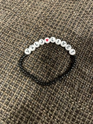 Svart pärlarmband med textpärlor - Coolt svart pärlarmband med vita bokstavspärlor som bildar texten 'VÄLJ LIVET' och ett rött hjärta. Armbandet är elastiskt och gjort av små svarta och vita plastpärlor. Perfekt accessoar för att uttrycka din stil och sprida ett positivt budskap.