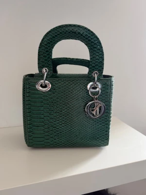 Grön handväska med ormskinnsmönster - Snygg grön handväska med ormskinnsmönster och silverdetaljer. 