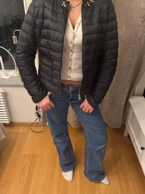 Svart pufferjacka med kort modell - Säljer en svart pufferjacka i kort modell med quiltad design och dragkedja framtill. Jackan har en stilren look och passar perfekt för kalla dagar. Inga synliga loggor eller märken på utsidan. Perfekt för dig som vill ha en enkel och snygg vinterjacka.