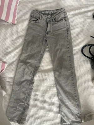 Grå raka jeans från BikBok - Säljer ett par grå jeans från BikBok med rak passform och hög midja. Jeansen har klassiska fem fickor, bälteshällor och knappgylf. Materialet är denim med en snygg tvättad look. Perfekta till en avslappnad stil. Använt 2 gånger endast