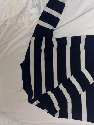 Randig stickad tröja i marinblått - Säljer en stickad tröja med breda marinblå och vita ränder. Tröjan har hög hals och långa ärmar, perfekt för en avslappnad och trendig look. Materialet känns mjukt och bekvämt, och passformen är lite oversized för extra komfort. Den är tight stickad o blir därför inte heller nopprig!!!  Säljer för att jag tröttnat på den. Vet inte vad den är köpt för men säljer för endast 270 kr!!!