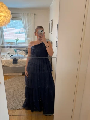 Marinblå balklänning från Y.A.S - Säljer min marinblå balklänning från Y.A.S med volangdetaljer och one shoulder. Klänningen är endast använd en gång och är därmed i väldigt bra skick. Den är i storlek M och nypris är 1349kr☺️