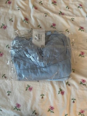 Bal klänning Hello Molly - Säljer en elegant ljusblå långklänning med smala axelband och v-ringad spetsdetalj vid bröstet. Klänningen har en slät och glansig yta som ger ett exklusivt intryck. Perfekt för dig som vill ha en stilren och feminin look och alldeles utmärkt för kommande bal!