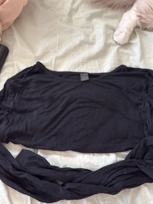 Svart croppad topp från Weekday - Svart croppad topp från shein med rund halsringning och långa ärmar. Tunn och mjuk i materialet, perfekt att styla med höga jeans eller kjol. Enkel och stilren design som funkar till många olika looks.