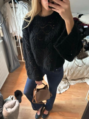 Svart chunky stickad tröja - Säljer en svart chunky stickad tröja med breda ärmar och hålmönster. Tröjan har en avslappnad passform och rund halsringning. Perfekt för lager på lager och ger en cool vibe till din outfit.