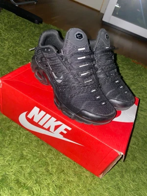 Nike tn - Nike Air Max Plus sneakers i helsvart med mesh- och syntetmaterial, ikoniska vågiga detaljer och synlig Air Max-dämpning i sulan. Snygg och sportig design med svarta skosnören och diskret Swoosh-logga på sidan. Perfekta för dig som gillar streetwear och komfort. Nytt pris för de är 200$