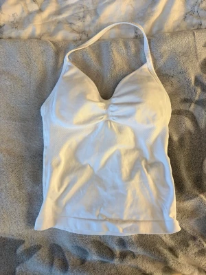 Vit halterneck topp GTECH - Säljer en vit halterneck topp från GTECH. Toppen har en åtsittande passform, har inbyggda inlägg vid bysten så man behöver ingen bh💓Materialet är stretchigt och andas, perfekt för träning eller gym. GTECH-logga på ryggen. Säljer för att den är för liten för mig🩷