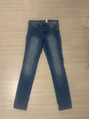 Skinny-jeans från HM - Säljer ett par ljusblå jeans med raka ben och klassisk femficksdesign. Jeansen har en snygg tvätt med lätt slitning på låren och knäna. Perfekta till en avslappnad stil och passar till det mesta i garderoben. Stl 30/32