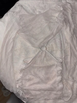 Beach cover-up - Den har öppen rygg och är öppen vid sidorna. Med små detaljer.