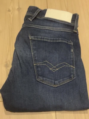 Mörkblå jeans från Replay - Snygga mörkblå jeans från Replay med klassisk femficksdesign och kontrastsömmar på bakfickan. Dom är tillverkade i denim med stretch för extra komfort. Perfekta för en trendig och avslappnad look.