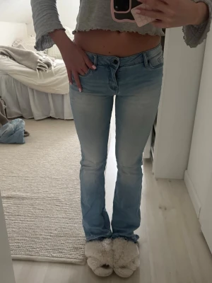 Ljusblå bootcut jeans - Säljer ett par ljusblå, lowwaist bootcut jeans med klassisk femficksmodell och låg midja. Jeansen har en snygg tvättad look och är tillverkade i denim med lite stretch för skön passform. Perfekta till en avslappnad stil och passar till det mesta. Trasiga längst nedtill annars helt perfekta!!❤️❤️