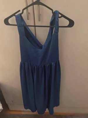 Blå ärmlös klänning med v-ringning - Snygg blå klänning med v-ringad hals och breda axelband. Modellen är ärmlös och har en utställd kjol som ger en avslappnad och trendig look. Perfekt för varma dagar och enkel att styla med accessoarer. För mer bilder/justering av pris skriv gärna❤️🤗