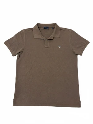 pikétröja Gant - En brun pikétröja från Gant. Tröjan är i storlek L men passar även M. Säljs då den inte passar mig. Inga defekter alls. Perfekt för sommaren. Hör av er vid frågor! 