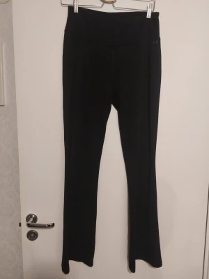Svarta bootcut leggings från SOC - Svarta leggings från SOC med bootcut-modell och diskret logga på höften. Mjukt och stretchigt material som sitter skönt och följer kroppen. Perfekta för en sportig och avslappnad stil.Andvända en gång.Inga defekter.