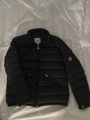 Svart dunjacka från Moncler  - Dunjacka från Moncler i färgen svart använd ett fåtal gången och är i mycket bra skick skulle säga att den är som ny