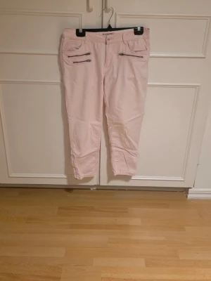 Ljusrosa piratbyxor med dragkedjor - Snygga ljusrosa jeans med raka ben och coola dragkedjedetaljer framtill. Jeansen har normal midja och flera fickor. 