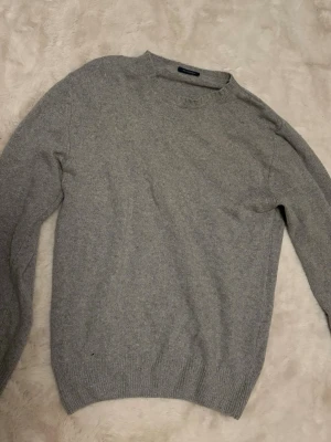 Grå stickad tröja 100% kashmir - Mysig grå stickad tröja med rund hals och långa ärmar. Tröjan har ribbade muddar vid ärmslut och nederkant, vilket ger en klassisk och enkel look. Perfekt för kyliga dagar och lätt att matcha med olika outfits. Köpt i italien. Storlek L men passar M bättre