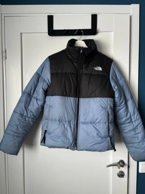 Blå och svart pufferjacka The North Face - Snygg pufferjacka från The North Face i ljusblått och svart. Är perfekt vinterjacka och har inga skador endast lite missfärgningar. 