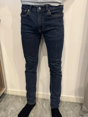 Mörkblå skinny jeans  - Säljer ett par mörkblå skinny jeans från Nudie Jeans med klassisk femficksmodell och snygga kontrastsömmar. Jeansen har en smal passform och är tillverkade i stretchig denim för extra komfort. Från dressman