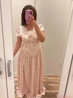 Viral blommig maxiklänning XS – Perfekt till midsommar & sommar - Säljer denna otroligt fina blommiga maxiklänning som tyvärr aldrig kommit till användning. Helt ny och i perfekt skick! 💕  Den har en romantisk och feminin passform med söta puffärmar, vackra detaljer framtill och ett underbart fall som verkligen gör att den sticker ut. Perfekt till midsommar, sommarfester, semester, picknickar eller när du bara vill känna dig extra fin. 🌷☀️  📏 Storlek: XS 🏷️ Från Temu ✨ Skick: Aldrig använd  Klänningen är lite längre i modellen, vilket ger en elegant och lyxig ma