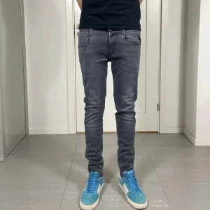 Replay anbass - Snygga grå slim fit jeans med klassisk femficksdesign och normal midja. Jeansen har en tvättad look och smal passform som sitter tajt längs benen. Perfekta för en trendig och avslappnad stil.