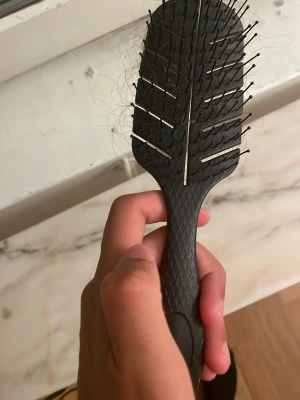 Svart hårborste med ventilerad design - En svart hårborste med ventilerad design och metallpiggar. Handtaget har ett greppvänligt mönster och borsten är perfekt för att reda ut håret smidigt. Passar både långt och kort hår.