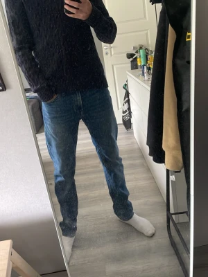 Mörkblå kabelstickad tröja Polo Ralph Lauren - Mörkblå kabelstickad tröja från Polo Ralph Lauren med halv dragkedja och röd logga broderad på bröstet. Tröjan har ribbstickad krage med röda ränder på insidan och är tillverkad i mjukt material. Perfekt för en stilren och klassisk look. Finns tecken på användning.