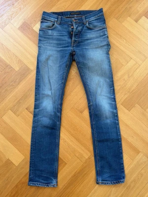 Blå Nudie Jeans Grim Tim - Snygga blå jeans från Nudie i modellen Grim Tim. Storleken är W29 L32 och skicket är förövrigt gott! Hör av dig vid minsta fundering!
