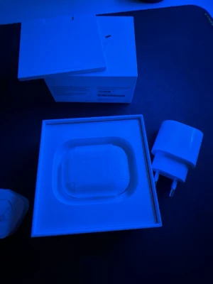 Apple AirPods Pro med laddningsetui - Säljer ett par vita Apple AirPods Pro med trådlöst laddningsetui. Hörlurarna har in-ear-design och levereras i originalförpackning tillsammans med laddare. Snygg och stilren design i plast, perfekt för dig som vill ha grymt ljud och smidig anslutning till iPhone. (TAR EMOT BUD)