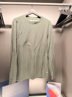 Samsøe samsøe - En stilren ljusgrön långärmad topp med rund halsringning. Tillverkad i mjuk bomull som känns skön mot huden. Perfekt för dig som gillar minimalistisk och clean stil. Passar till jeans eller kjol för en enkel look.