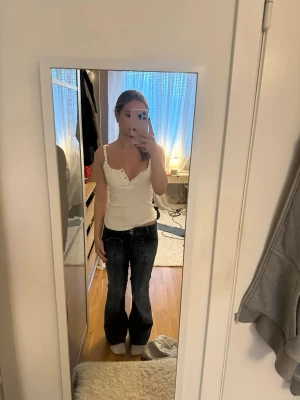 Mörkblå bootcut jeans med vita sömmar - Säljer ett par mörkblå bootcut jeans med tydliga vita kontrastsömmar och låg midja. Jeansen har klassisk femficksdesign och är tillverkade i denim. Perfekta för en avslappnad och trendig look.