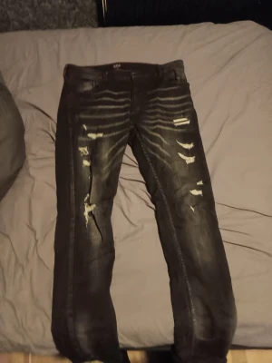 Svarta slitna jeans från Icon Milano - Säljer ett par svarta jeans från Icon Milano med slitningar och distressed detaljer framtill. Jeansen har skinny fit och klassisk femficksmodell. Materialet är denim med stretch för extra komfort. Perfekta för en trendig och avslappnad stil.