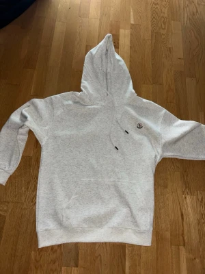 Ljusgrå hoodie från Moncler - Säljer en stilren ljusgrå hoodie från Moncler med klassisk huva som jag fick för några månader sen av min kompis. Skönt material perfekt för lite kallare sommardagar. Bara att höra av er vid funderingar