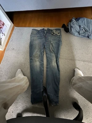 Slim fit blå jeans med slitningar G star - Snygga slim fit jeans i blå denim med slitningar och lätt tvättad look. Jeansen har klassiska fem fickor, låg midja och detaljerade sömmar. Perfekta för en avslappnad och trendig stil.