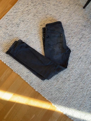 Extremt snygga Jack & Jones jeans 28/32 - Säljer ett par svarta slim fit jeans med klassisk femficksdesign. Jeansen har en snygg tvättad look och raka ben. Perfekta till en avslappnad stil och passar till det mesta i garderoben.