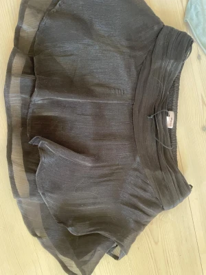 Svart volangkjol med resårmidja - Säljer en svart kortkjol med volanger och bred resår i midjan. Kjolen har ett skirt, lätt transparent yttertyg som ger en luftig känsla och snyggt fall. Perfekt att styla med en enkel topp eller hoodie.💗