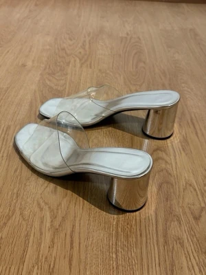 Genomskinliga silvriga klackar  - Trendiga sandaler med genomskinliga plastrem och silvrig klack. Storlek 39 men är för små i storlek💕