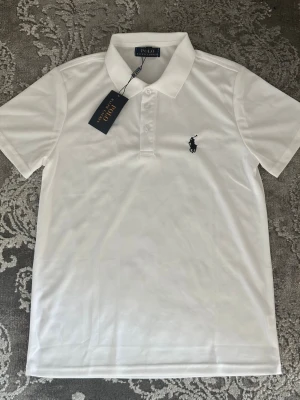 Ralph Lauren pike - Stilren vit Ralph pikétröja med krage, helt ny oanvänd. Tillverkad i mjuk bomull som känns skön mot huden. Perfekt till jeans eller shorts för en clean och stilren look, pris kan diskuteras vid snabb affär.