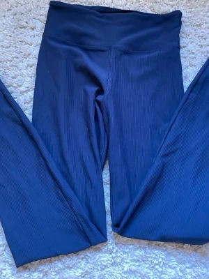 Mörkblå ribbade träningstights från röhnisch  - Mörkblå leggings med ribbad struktur och hög midja. De har 3 hål som är ganska små men därav priset. 